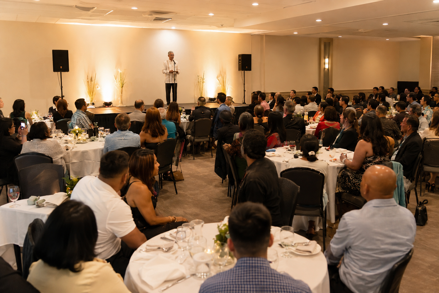 A modest celebration setup with stage, speakers, seating and warm lighting